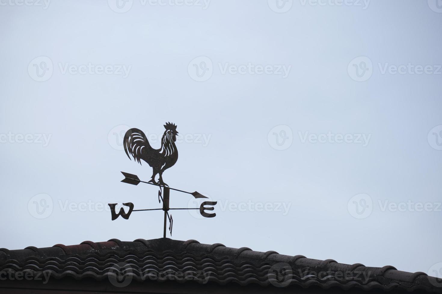 l'ancienne girouette avec une icône de symbole de coq sur le toit, équipement technologique traditionnel pour prévoir et mesurer le temps venteux dans l'air, décoration vintage, instrument de direction du vent visant. photo