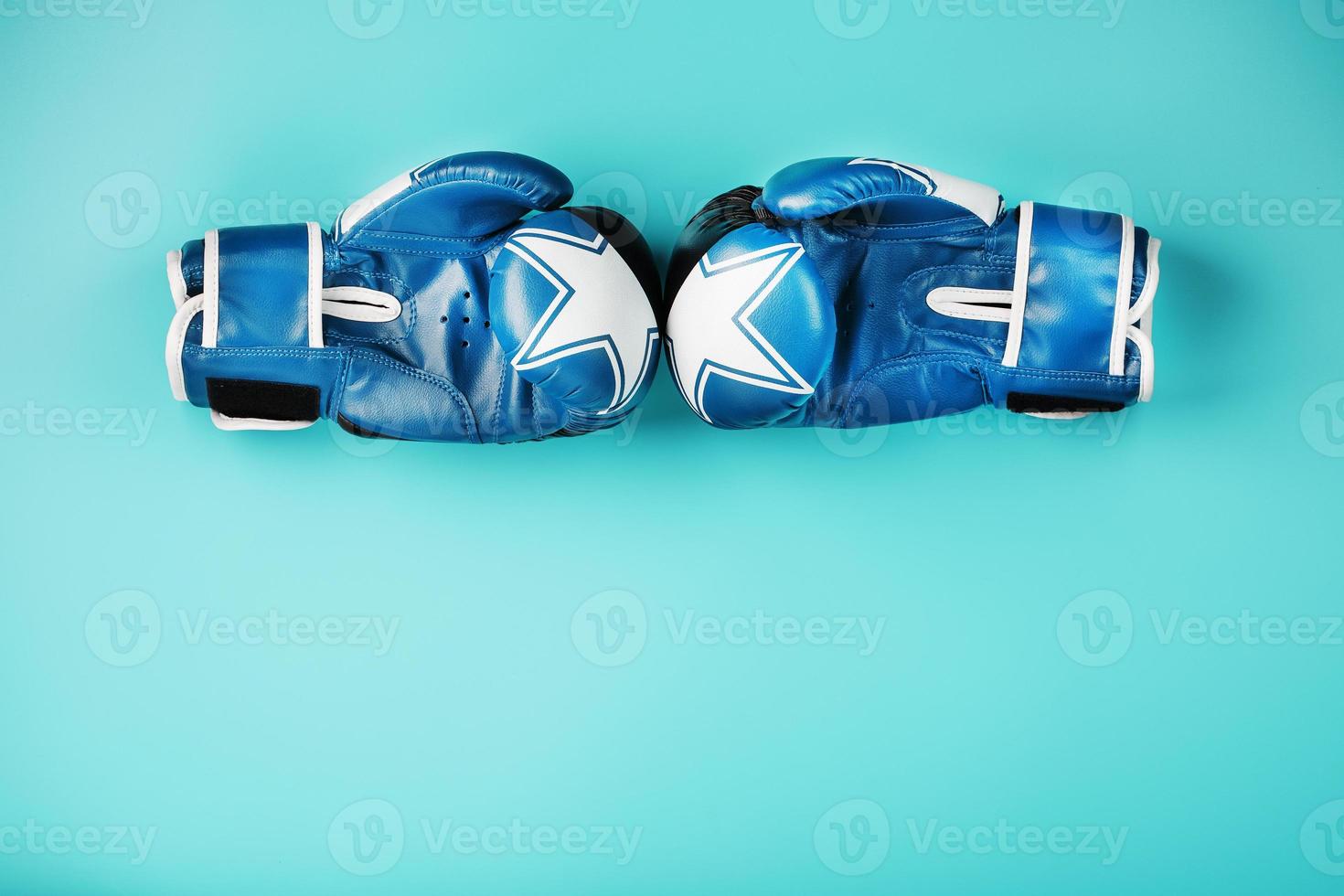 une paire de gants bleus de boxe se faisant face sur un fond bleu. photo