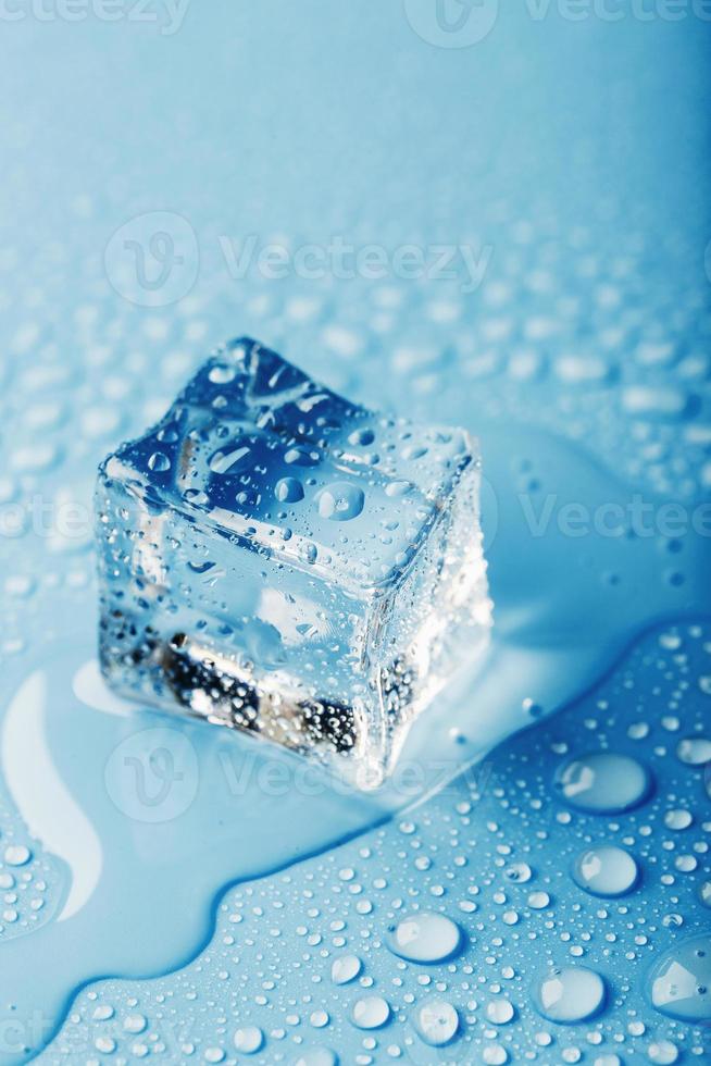 cubes de glace en gros plan avec des gouttes d'eau de fonte dispersées sur un fond bleu. photo