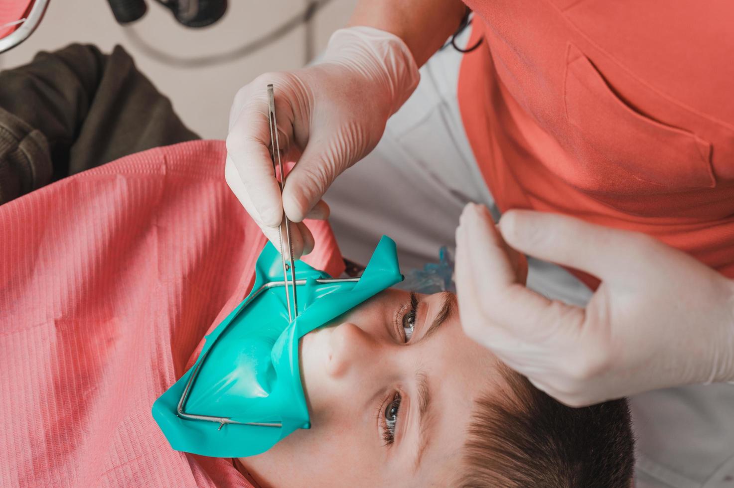 le dentiste traite la dent de l'enfant à l'aide d'une digue en caoutchouc. photo