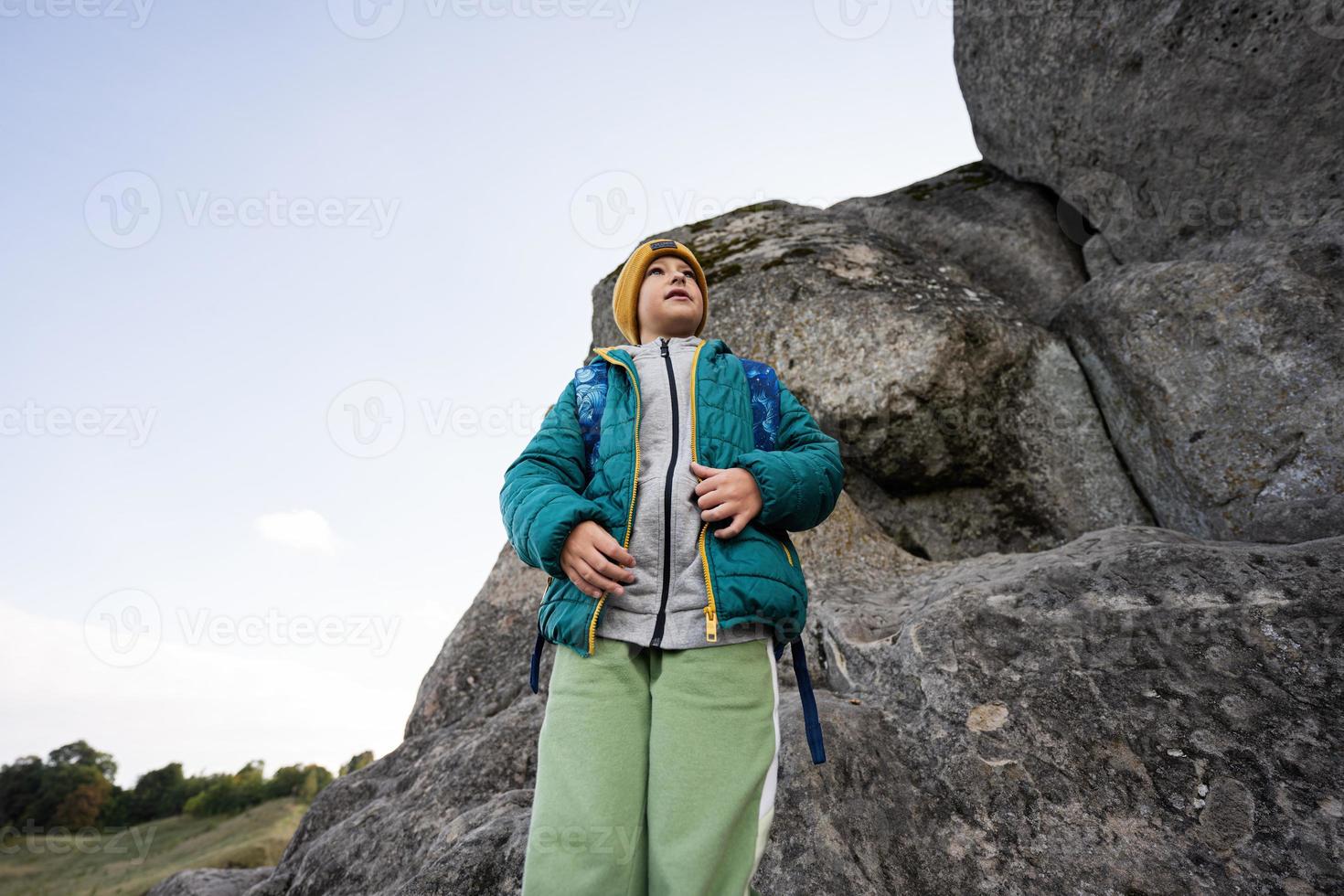 garçon avec sac à dos escalade grosse pierre dans la colline. pidkamin, ukraine. photo
