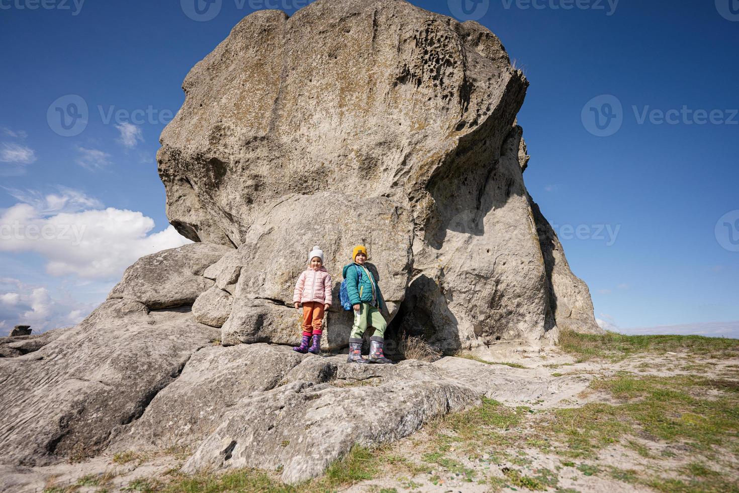 explorer la nature. frère et soeur portent un sac à dos en randonnée près d'une grosse pierre dans la colline. pidkamin, ukraine. photo