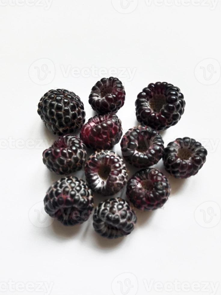 framboises noires juteuses mûres sur fond blanc photo