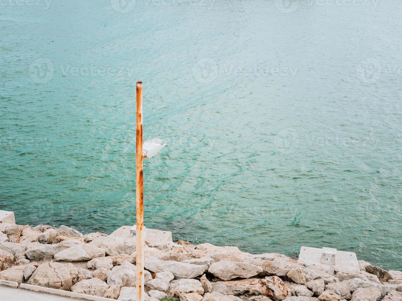 Lonley lanterne rouillée sur un rivage rocheux de la mer photo