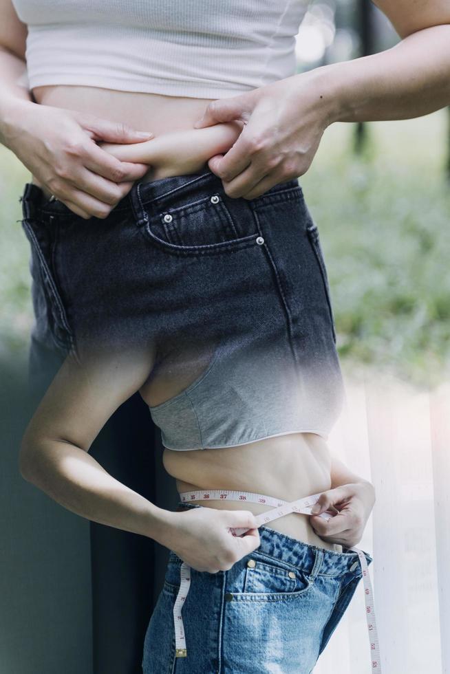 belle grosse femme avec ruban à mesurer, elle utilise sa main pour presser l'excès de graisse isolé sur fond blanc. elle veut perdre du poids, le concept de chirurgie et décomposer les graisses sous le photo