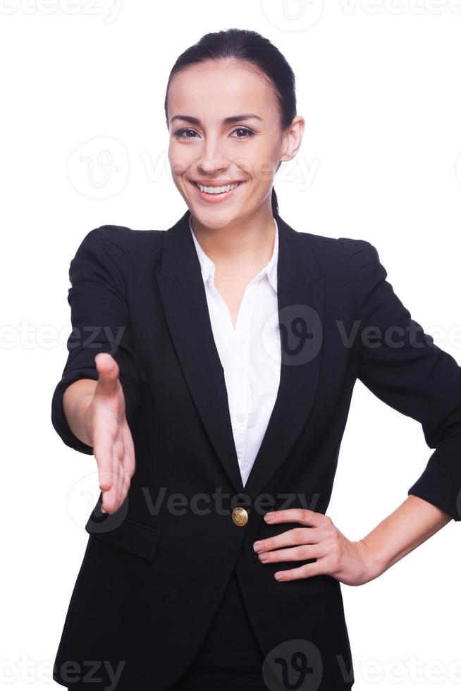 Félicitations jeune femme confiante en tenues de soirée tendant la main pour serrer et souriant tout en se tenant isolé sur blanc photo