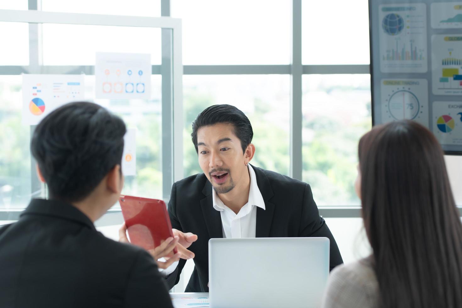 un groupe de jeunes entrepreneurs asiatiques. la haute direction se réunit pour examiner les données d'investissement en actions de l'équipe dans une salle de réunion à la lumière naturelle photo