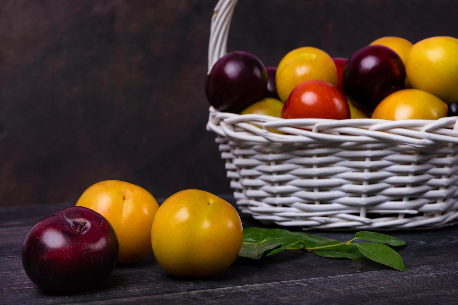 prunes colorées dans un panier sur fond sombre photo