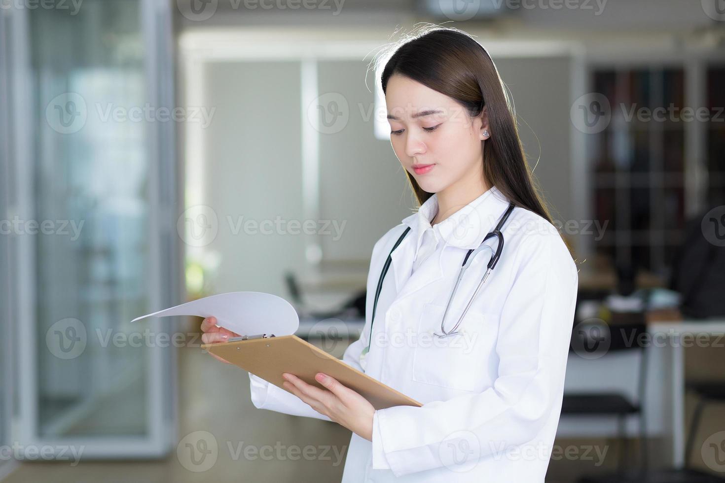 femme médecin asiatique regarde le document ouvert dans le presse-papiers photo
