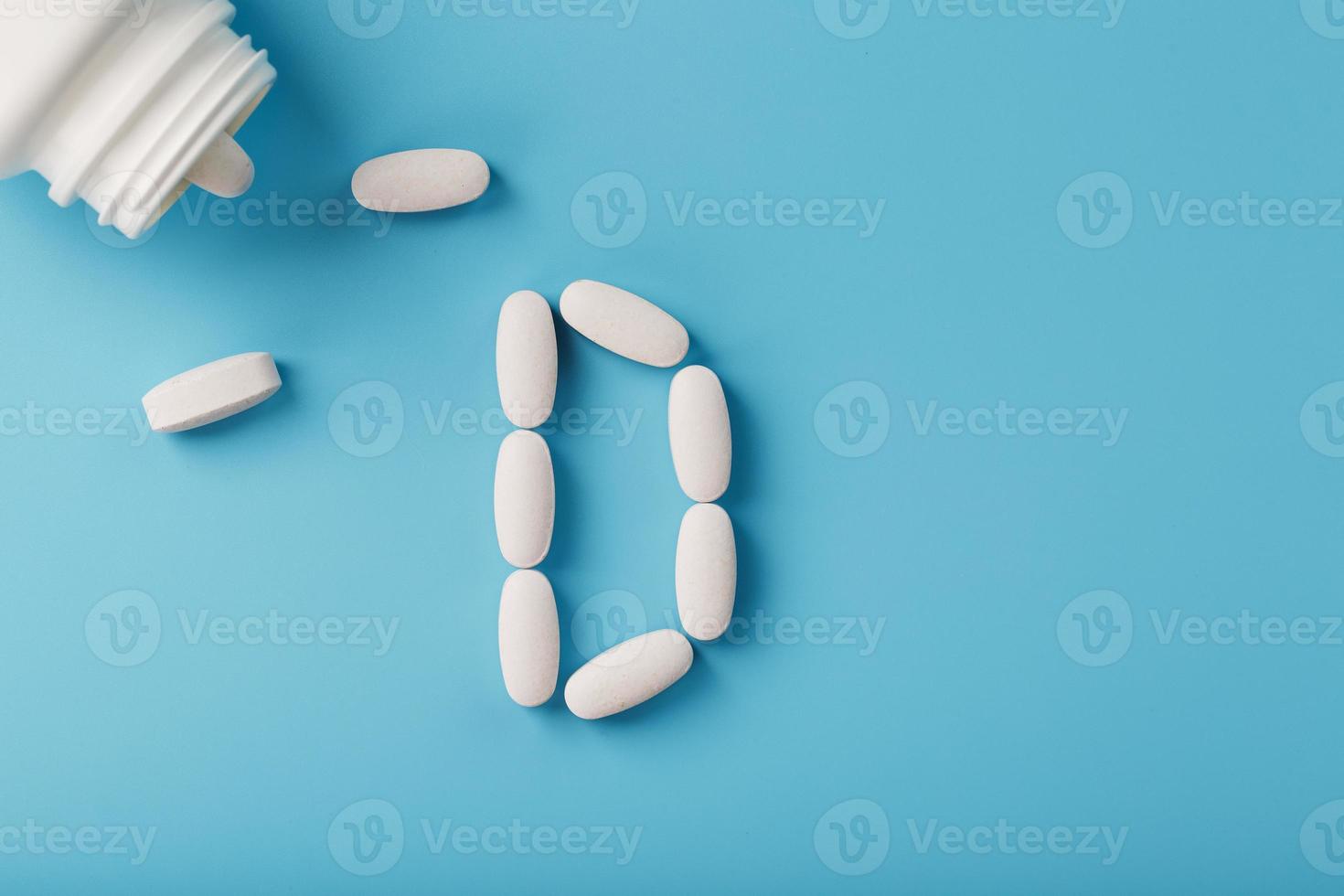 la lettre de vitamine d en capsules se déverse d'un pot sur fond bleu. photo