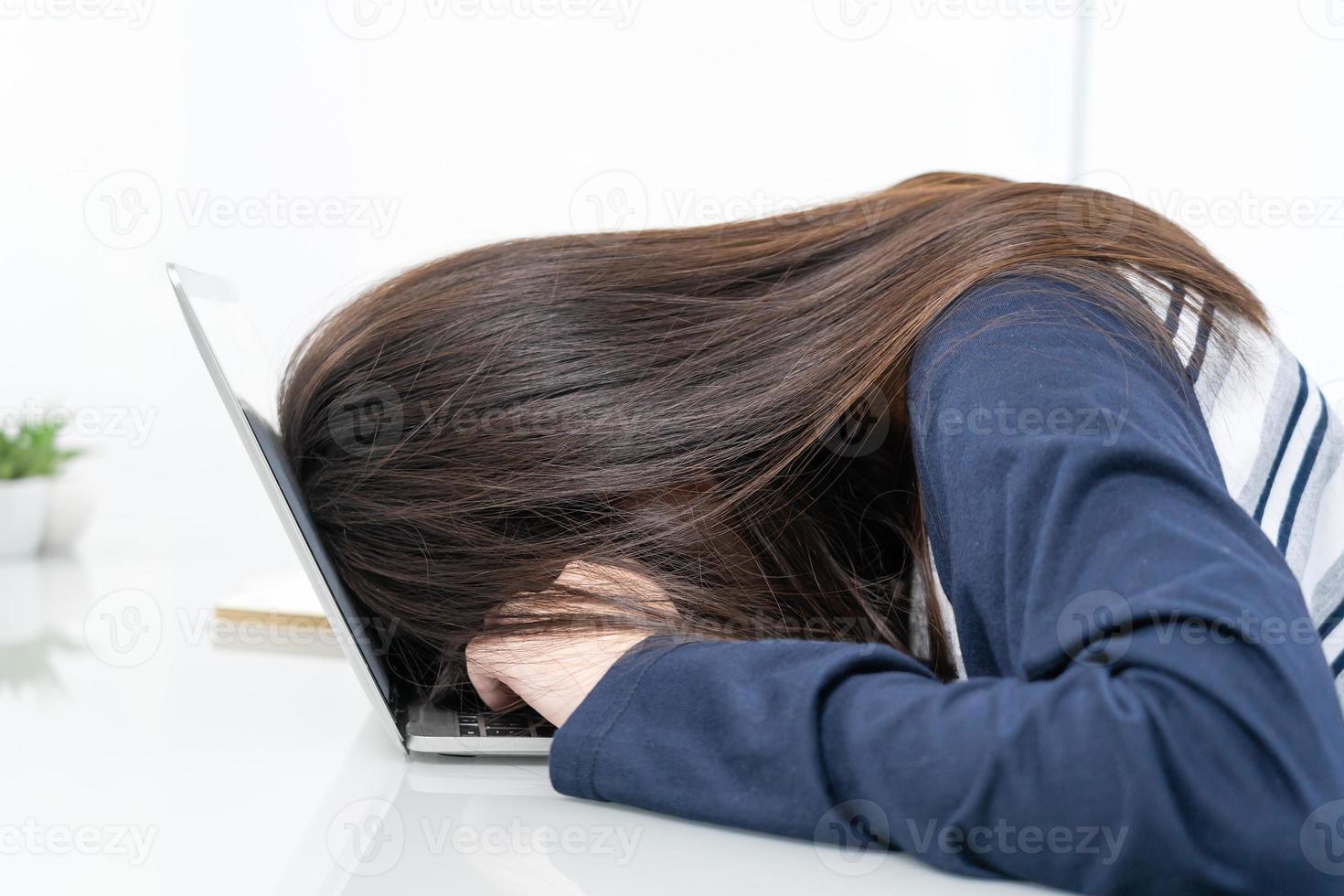 jeune femme cheveux longs s'endormir sur un bureau avec un ordinateur portable photo