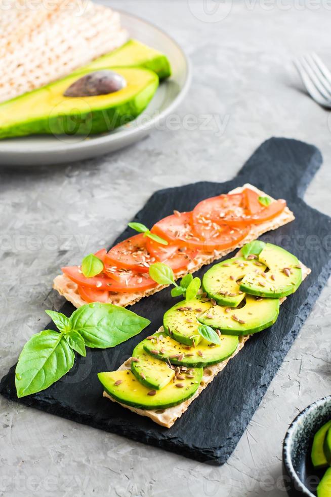 sandwichs appétissants à l'avocat et aux tomates sur pain de céréales sur ardoise. photo