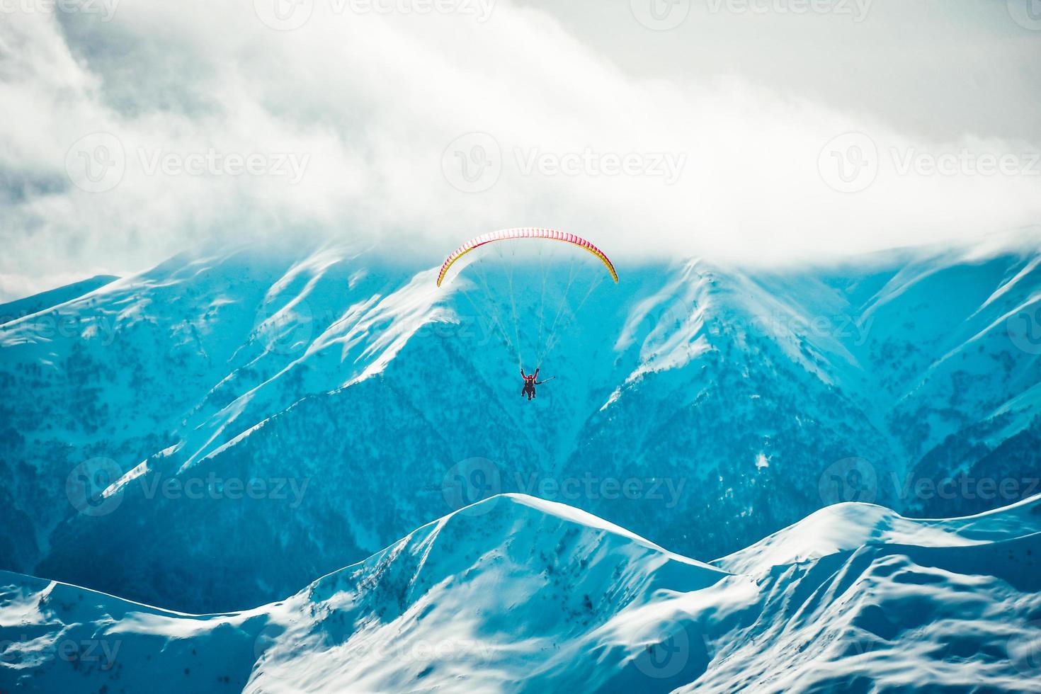 panorama de la station de ski de gudauri avec des parapentes en tandem haut dans l'air par une froide journée d'hiver avec fond caucase photo