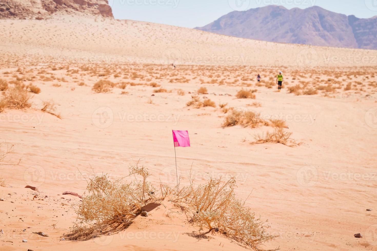 wadi rum, jordanie, 2022 - drapeaux et athlètes concurrents marchent rapidement dans les marquages du col du désert sur une chaleur extrême dans un ultra-marathon multi-étapes ultra x jordan difficile photo