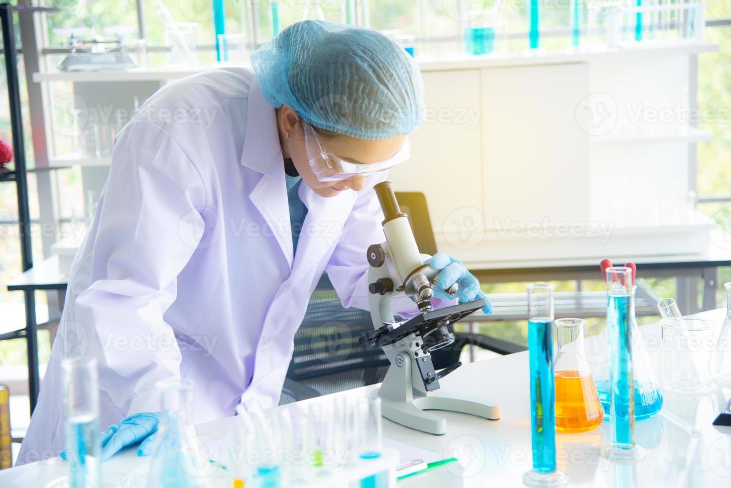 une scientifique, chercheuse, technicienne ou étudiante asiatique a mené des recherches ou des expériences à l'aide d'un microscope qui est un équipement scientifique dans un laboratoire médical, de chimie ou de biologie photo