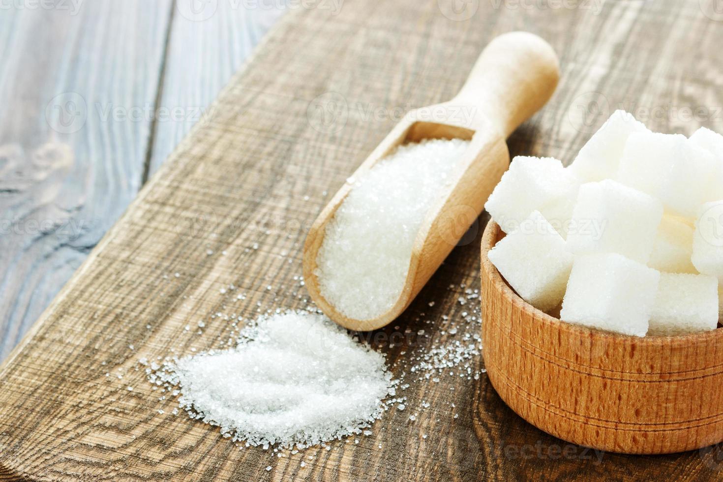 bol et cuillère avec du sable blanc et du sucre en morceaux sur fond de bois photo