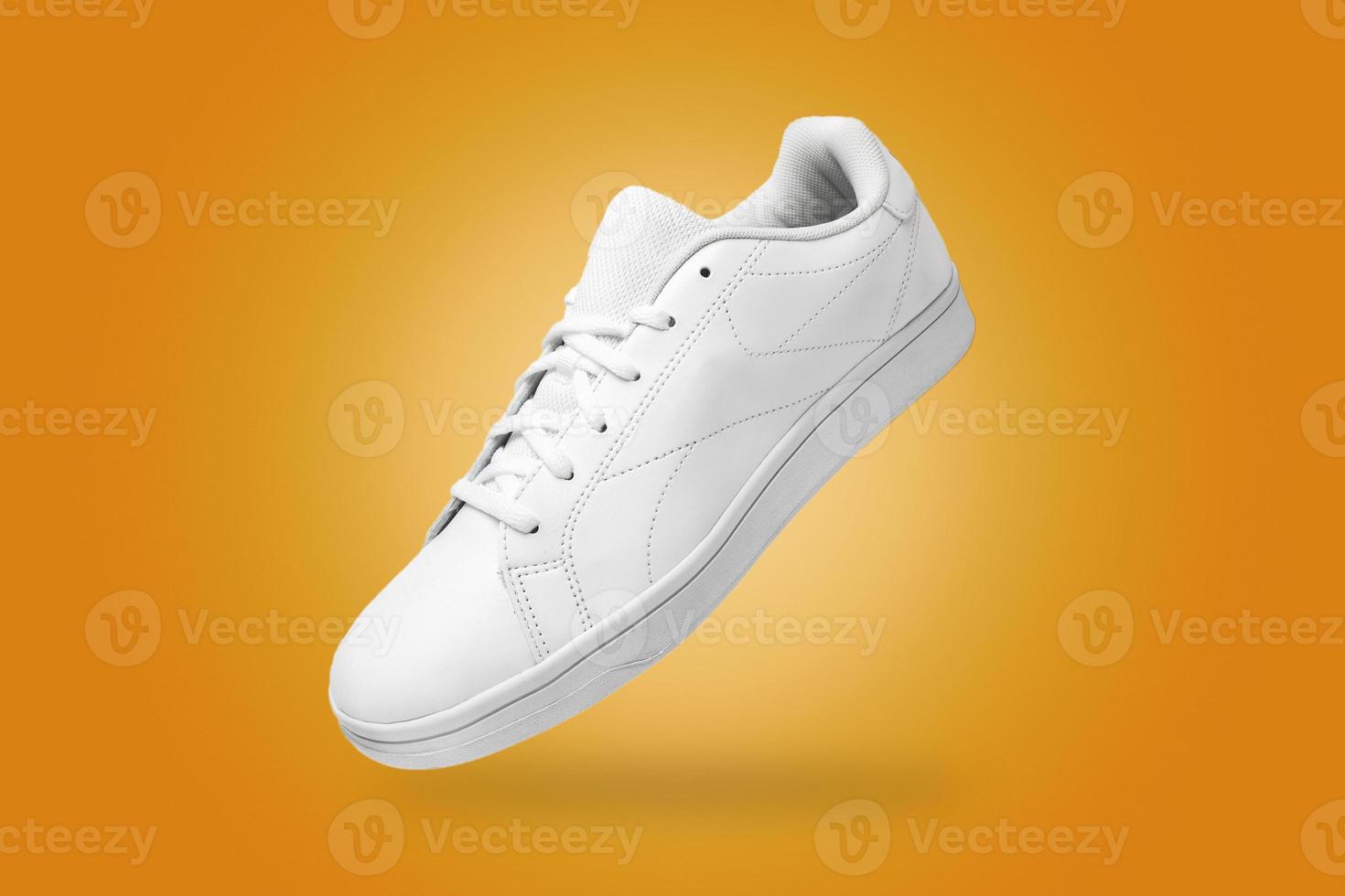 vue grand angle de baskets blanches isolées sur fond jaune. paire de chaussures sportives pour maquette. chaussures de sport élégantes à la mode. photo