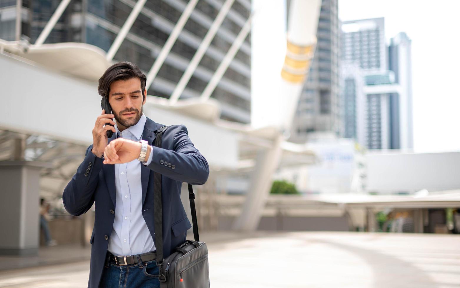 l'homme d'affaires parle avec un téléphone intelligent et regarde sa montre sur son chemin. se sentir heureux et relaxant, jeune homme d'affaires décontracté portant une veste de costume. photo