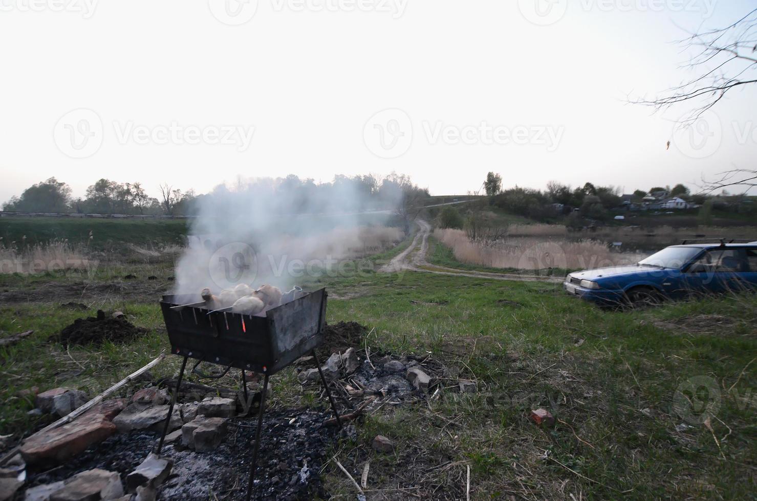 les brochettes d'ailes de poulet sont frites sur le terrain. un barbecue classique en plein air. le processus de friture de la viande sur du charbon de bois photo