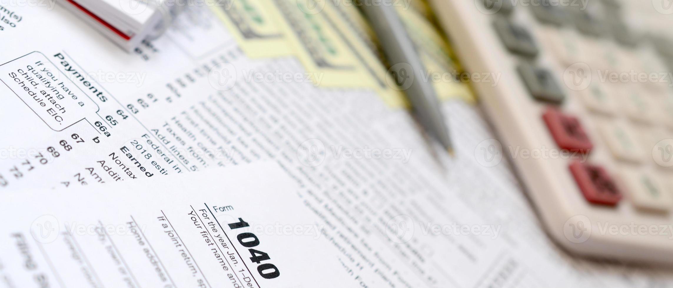 le stylo, le cahier, la calculatrice et les billets d'un dollar se trouvent sur le formulaire fiscal 1040 déclaration de revenus des particuliers américains. le temps de payer les impôts photo