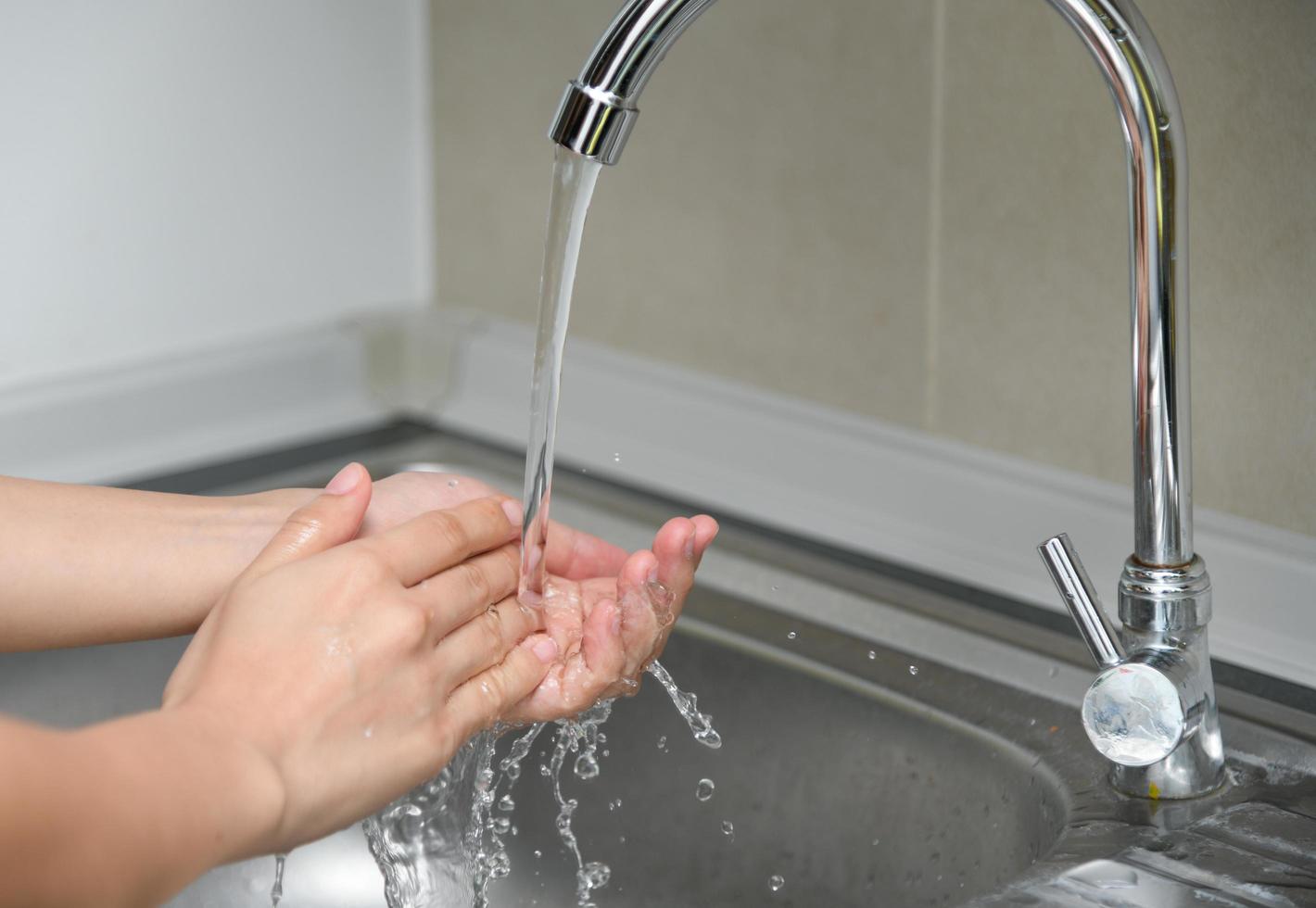 femme se lavant les mains dans un évier avec de l'eau du robinet photo