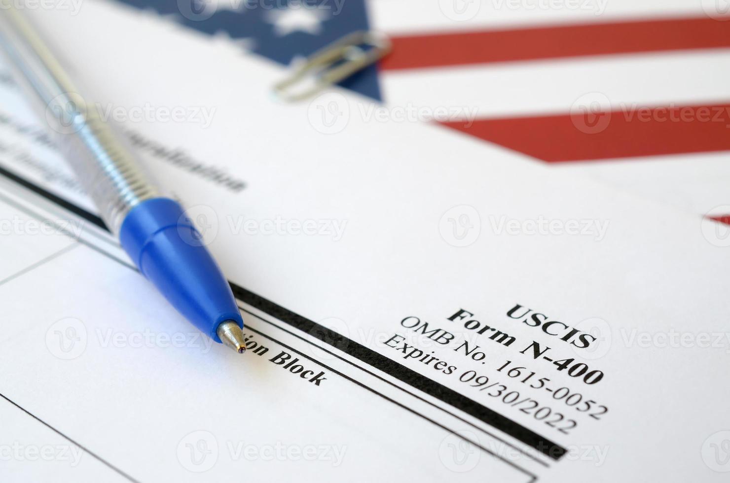 Le formulaire vierge de demande de naturalisation n-400 se trouve sur le drapeau des états-unis avec un stylo bleu du département de la sécurité intérieure photo