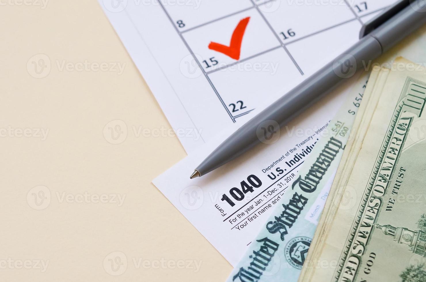 1040 formulaire de déclaration de revenus des particuliers avec chèque de remboursement et billets de cent dollars sur le calendrier avec marque le 15 avril photo