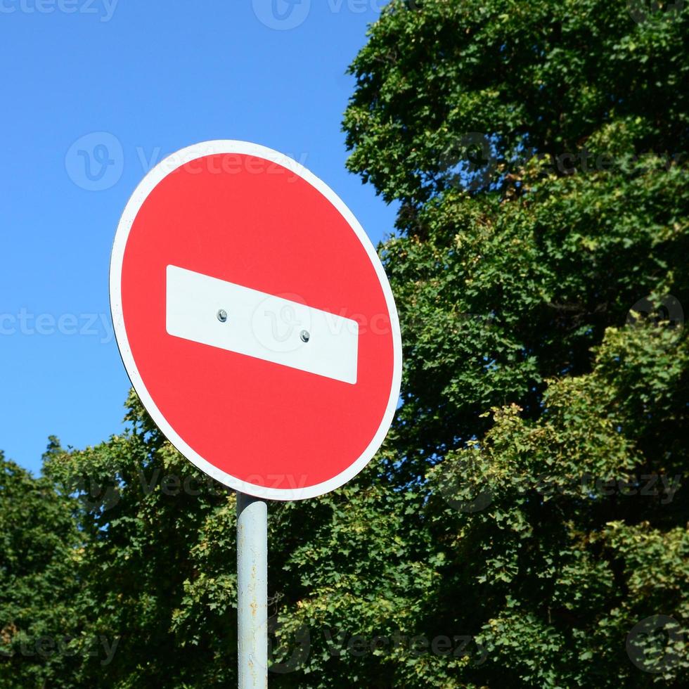 un panneau rouge circulaire avec une barre blanche indiquant qu'il est interdit d'entrer sur un poteau en métal gris photo