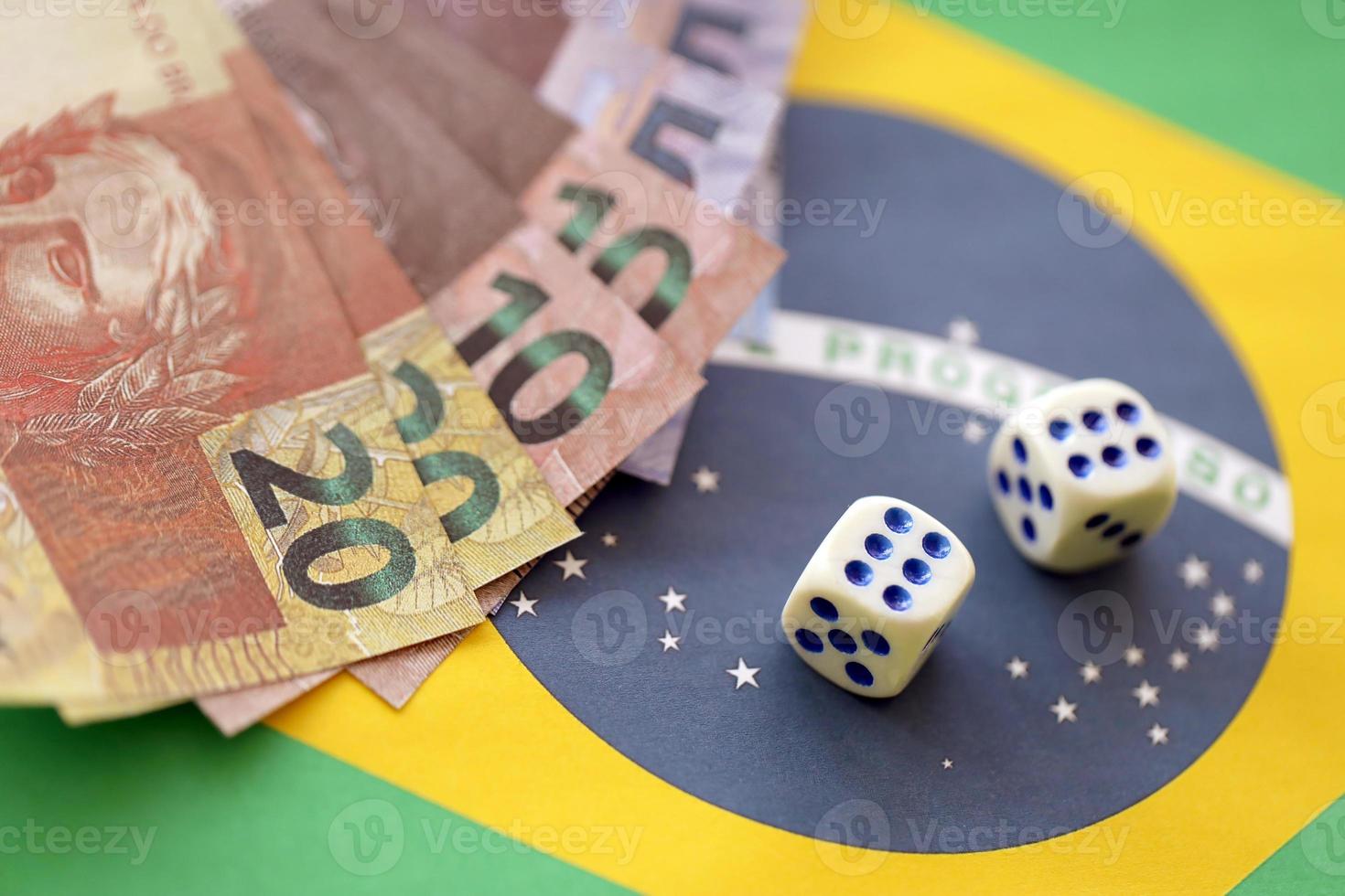 cubes de dés avec des billets d'argent brésiliens sur le drapeau de la république du brésil. concept de chance et de jeu au brésil photo