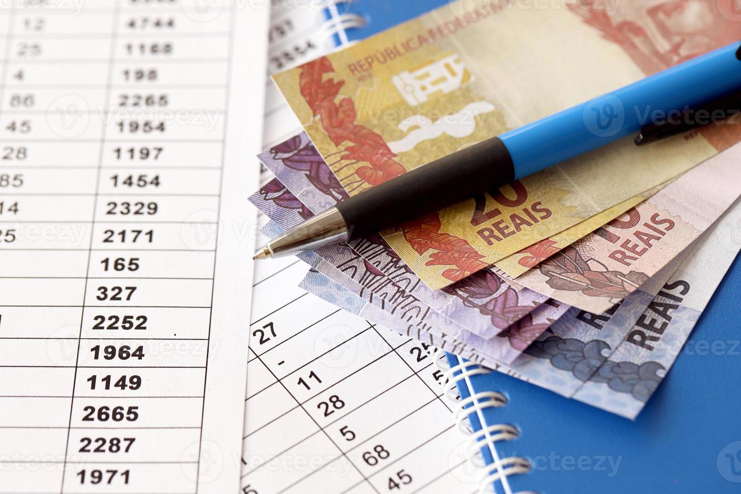 stylo avec reals brésiliens sur documents avec table de calculs. concept d'entreprise, de comptabilité ou de paiement d'impôts au brésil photo