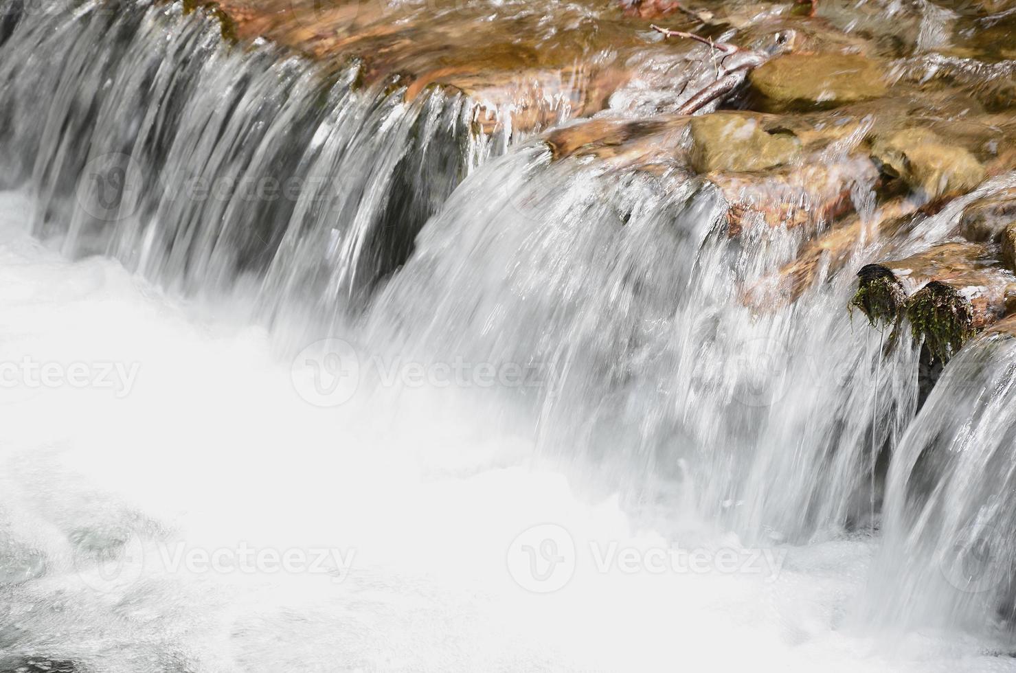 une petite cascade. la différence de hauteur du débit d'eau dans la rivière est équipée de bûches rondes en bois photo