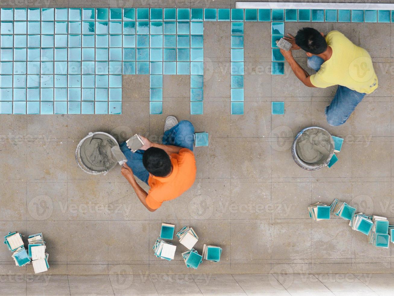 vue de haut niveau du carreleur installant des mosaïques sur la base de la piscine photo