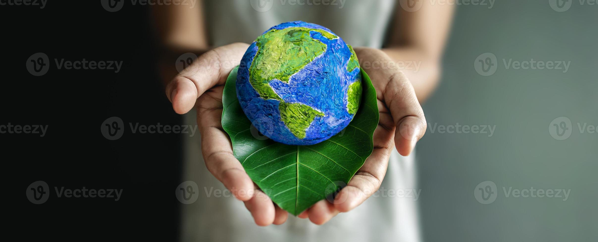 concept de la journée mondiale de la terre. énergie verte, ressources renouvelables et durables. protection de l'environnement et de l'écologie. main embrassant une feuille verte et un globe fait à la main photo