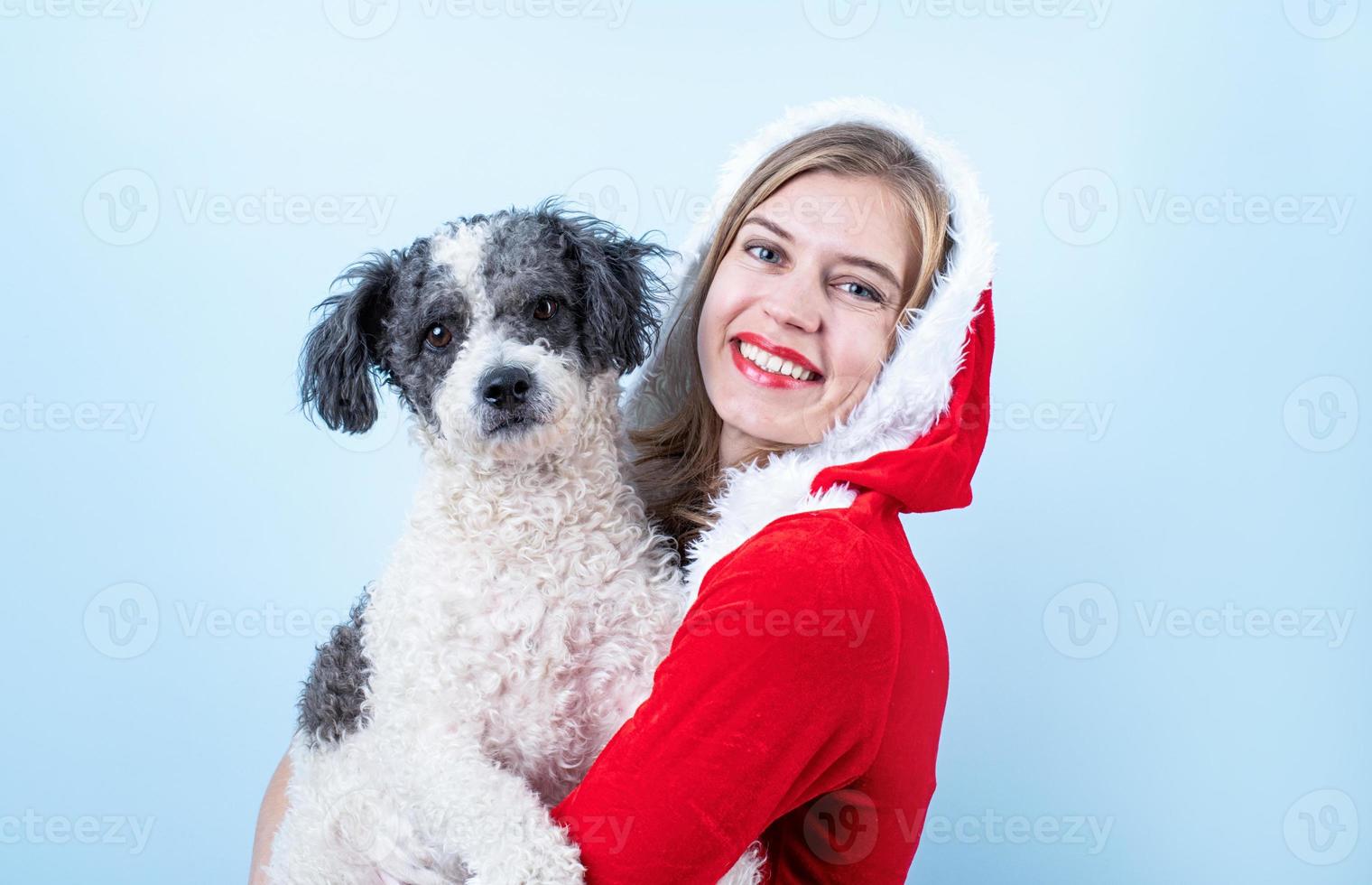 gros plan d'une femme heureuse caucasienne portant des vêtements de père noël tenant un chien mignon photo