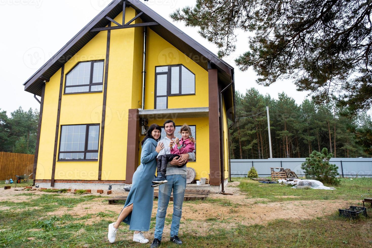 famille heureuse dans la cour d'une maison inachevée - achat d'un chalet, hypothèque, prêt, déménagement, construction photo