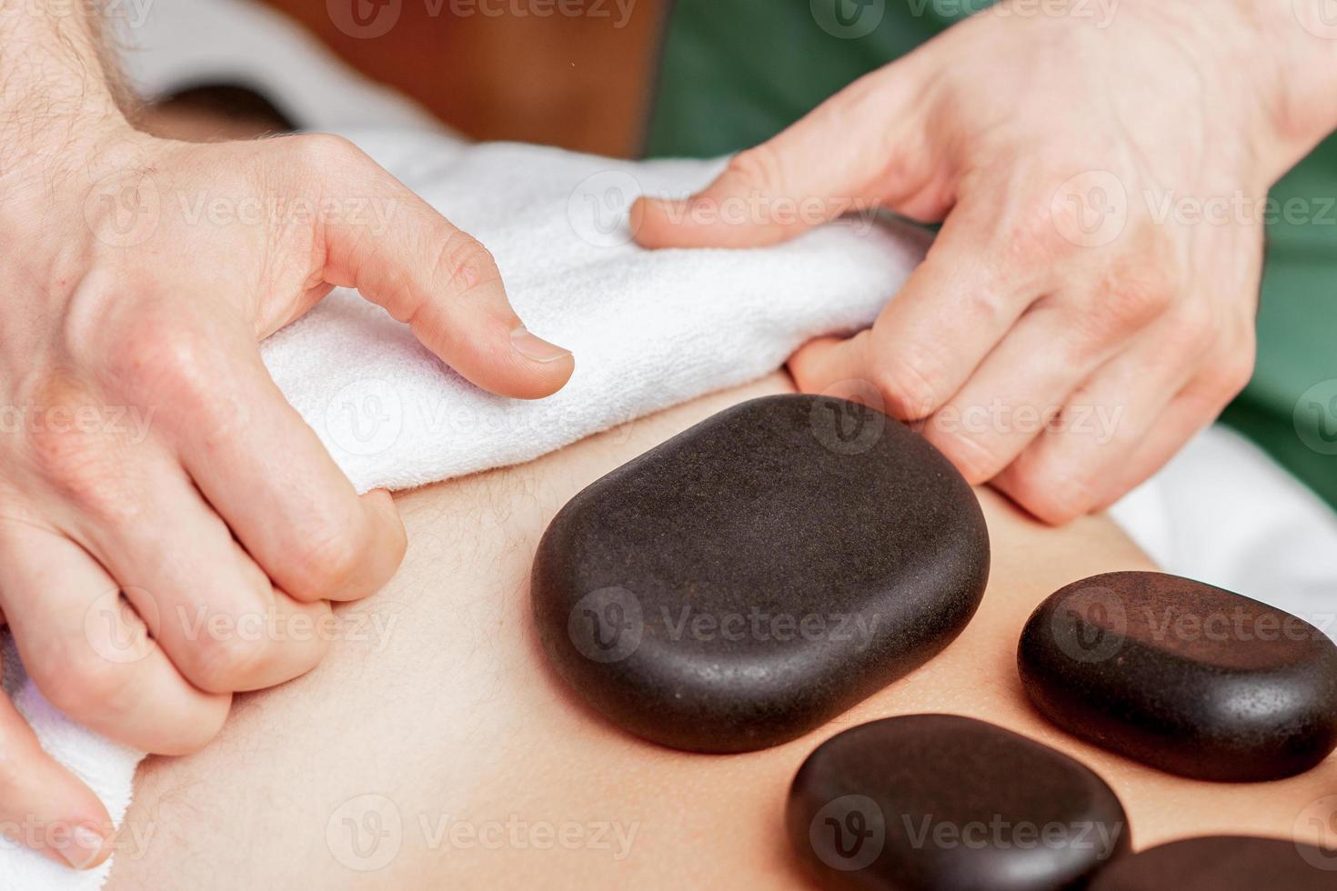 massage aux pierres sur le dos de l'homme. photo