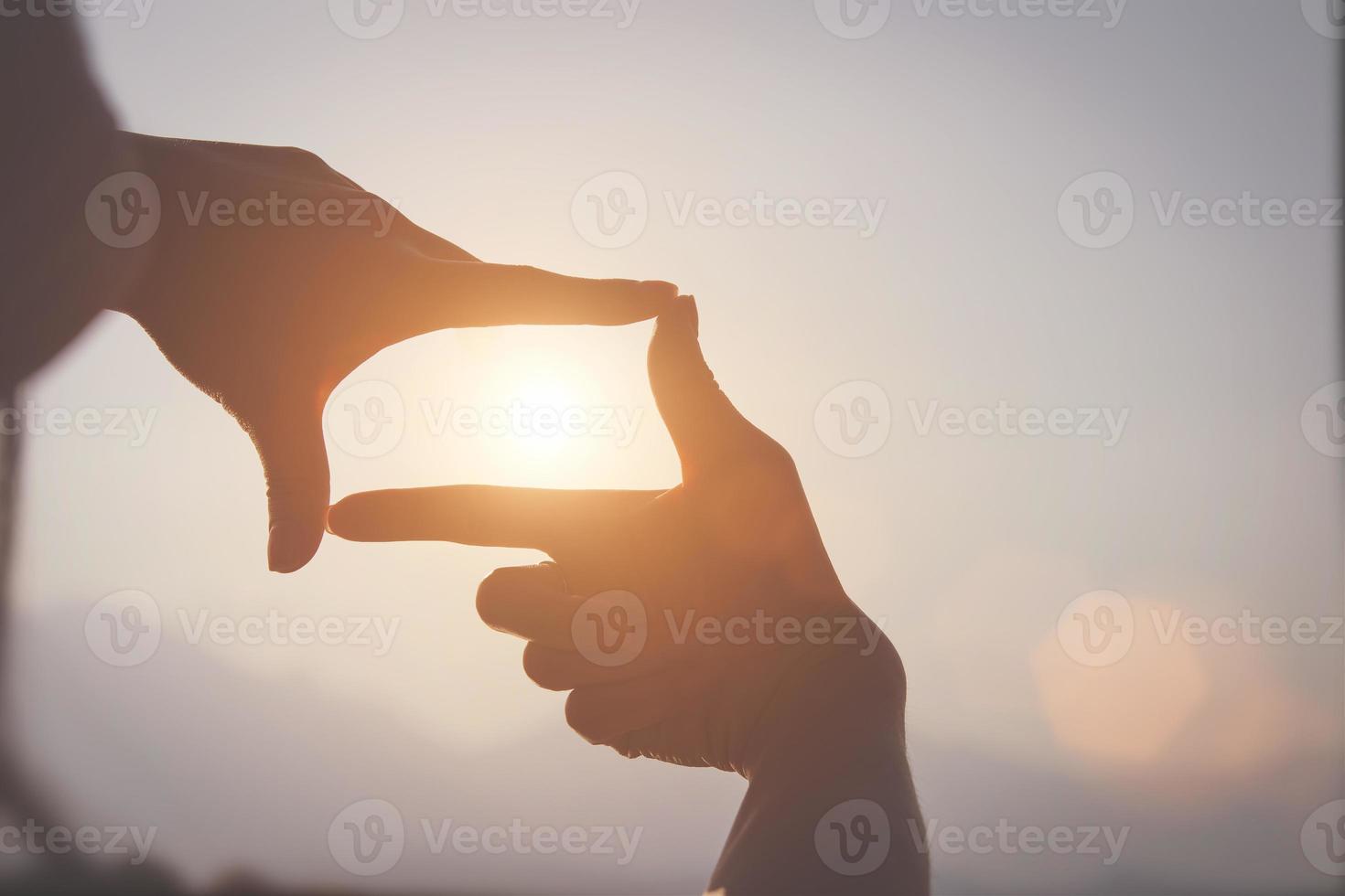 concept de planification et de vision du début de la nouvelle année, main de femme faisant un geste de cadre trouver la mise au point au coucher du soleil, femme à la recherche de perspective pour saisir le sens d'une cible claire à venir. photo