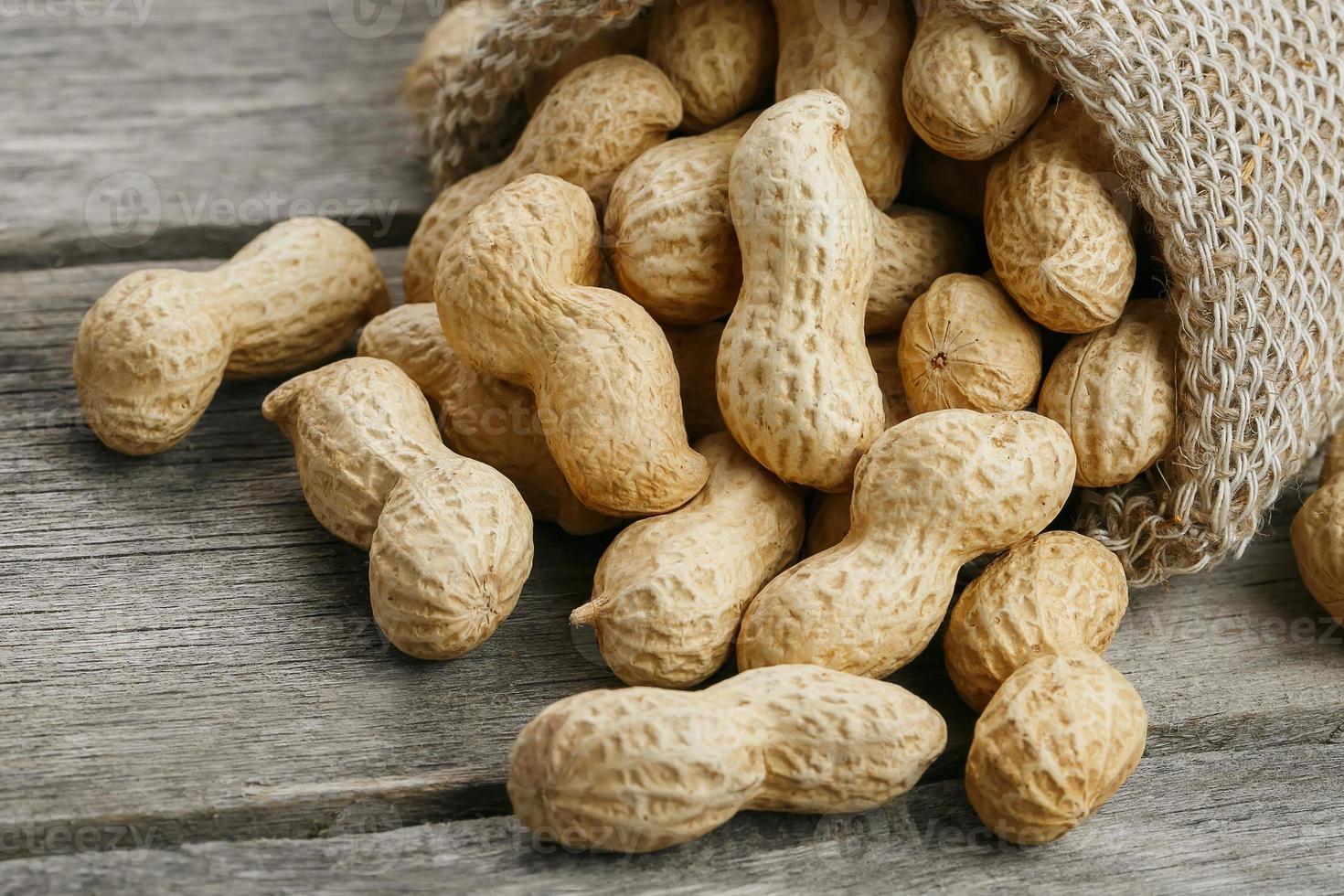 cacahuètes dans un sac de toile de jute miniature sur une vieille surface en bois grise photo