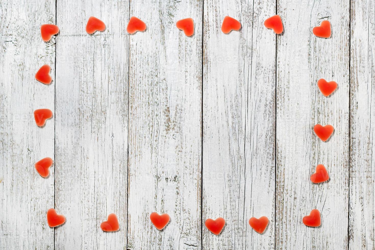 cadre fait de bonbons en forme de coeur rouge sur fond de bois blanc pour la saint valentin photo