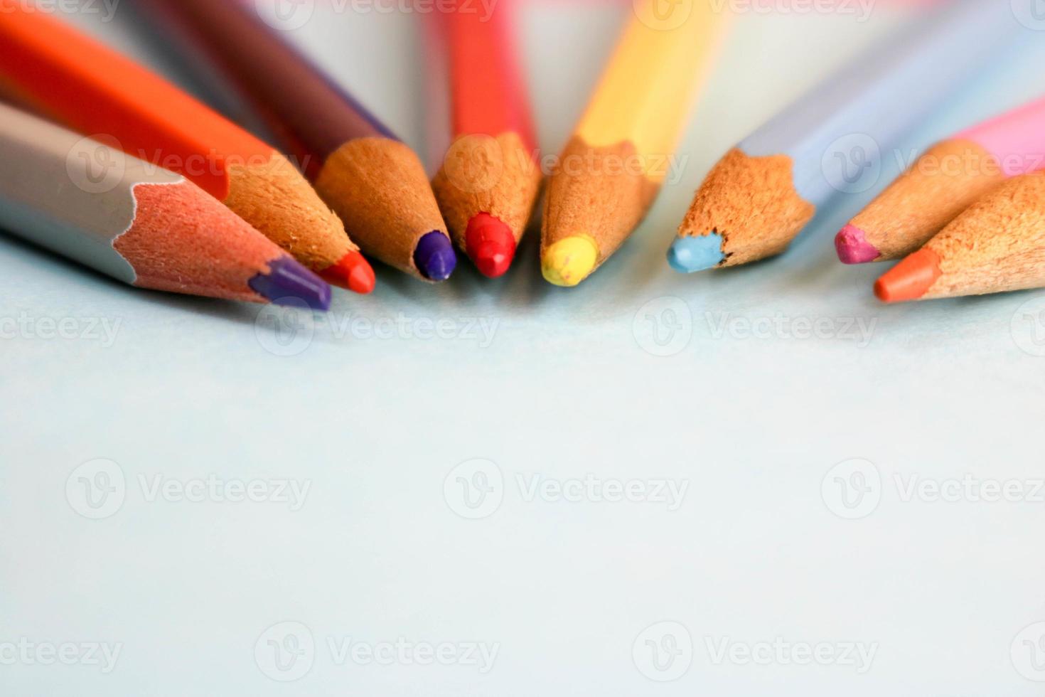 beaux crayons à tailler en bois de couleur vive pour le dessin. mise à plat et espace de copie sur fond bleu photo
