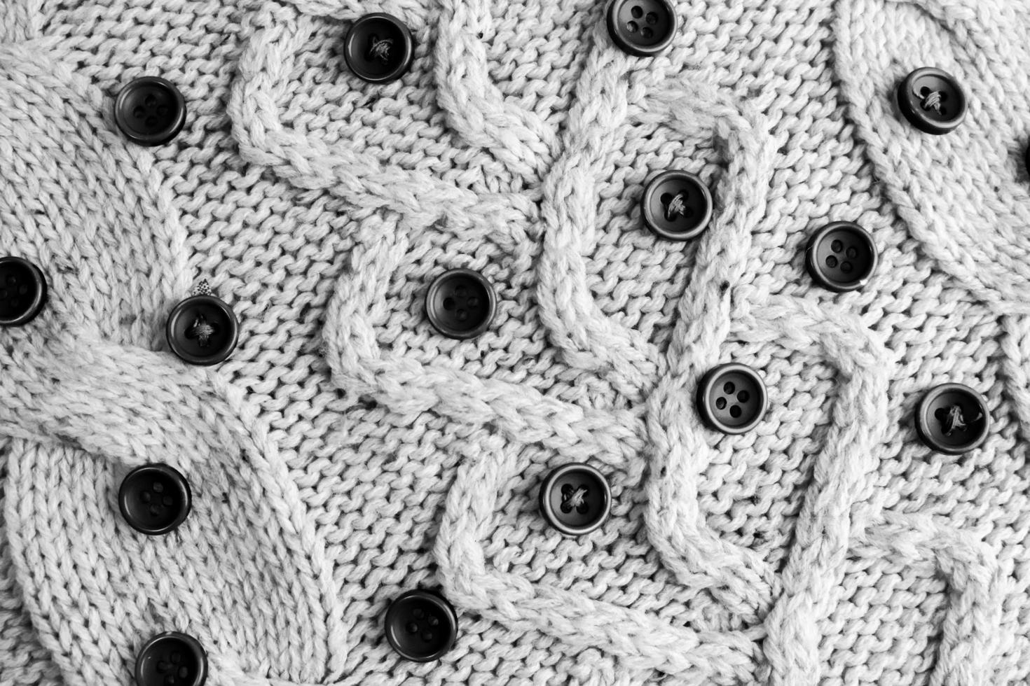 belle texture d'un pull naturel doux et chaud avec un motif tricoté de fil et de petits boutons ronds noirs et blancs. l'arrière-plan photo