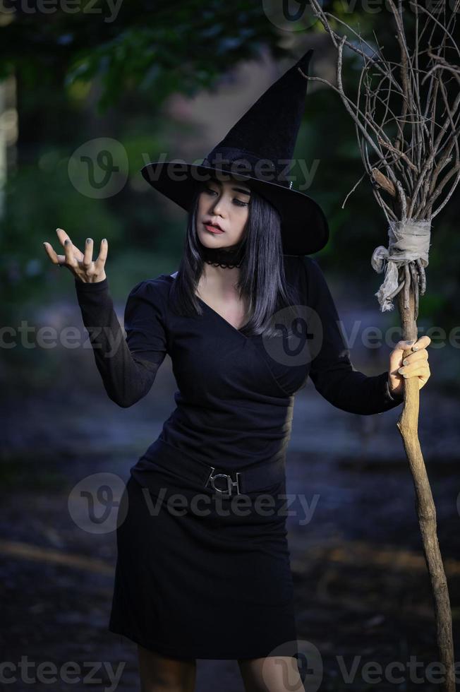 portrait de belle femme sexy asiatique porter un costume de sorcière noire avec balai, concept de festival d'halloween photo