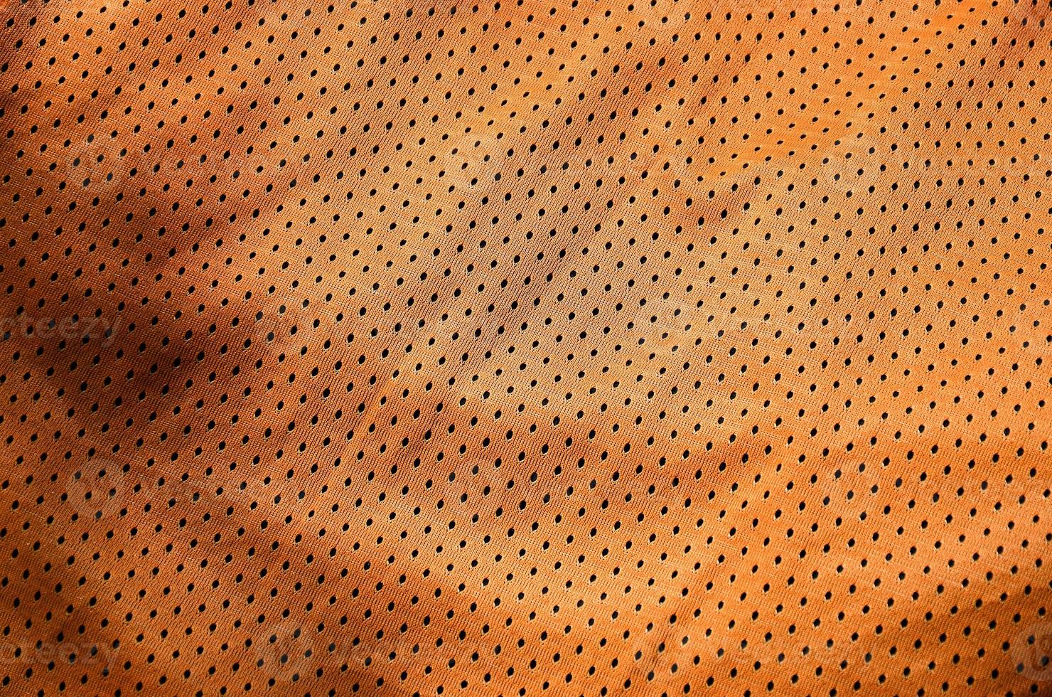 fond de texture de tissu de vêtements de sport. vue de dessus de la surface textile en tissu de nylon polyester orange. maillot de basket coloré avec espace libre pour le texte photo