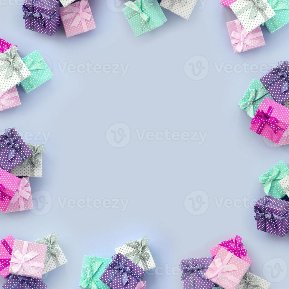 des piles de petites boîtes cadeaux colorées avec des rubans se trouvent sur un fond violet photo