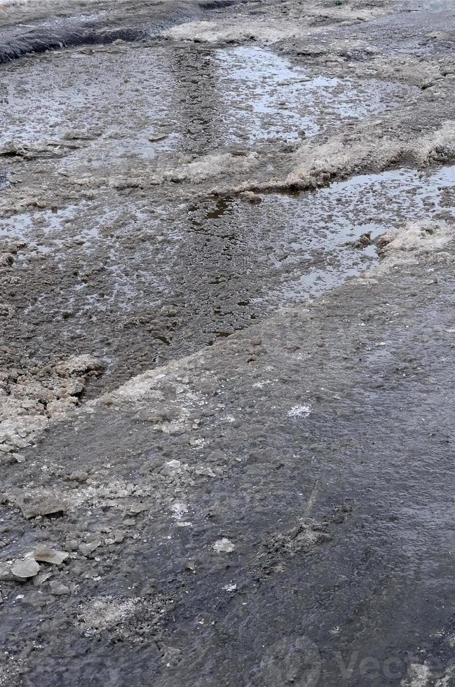 route asphaltée endommagée avec des nids-de-poule causés par les cycles de gel et de dégel pendant l'hiver. mauvaise route photo
