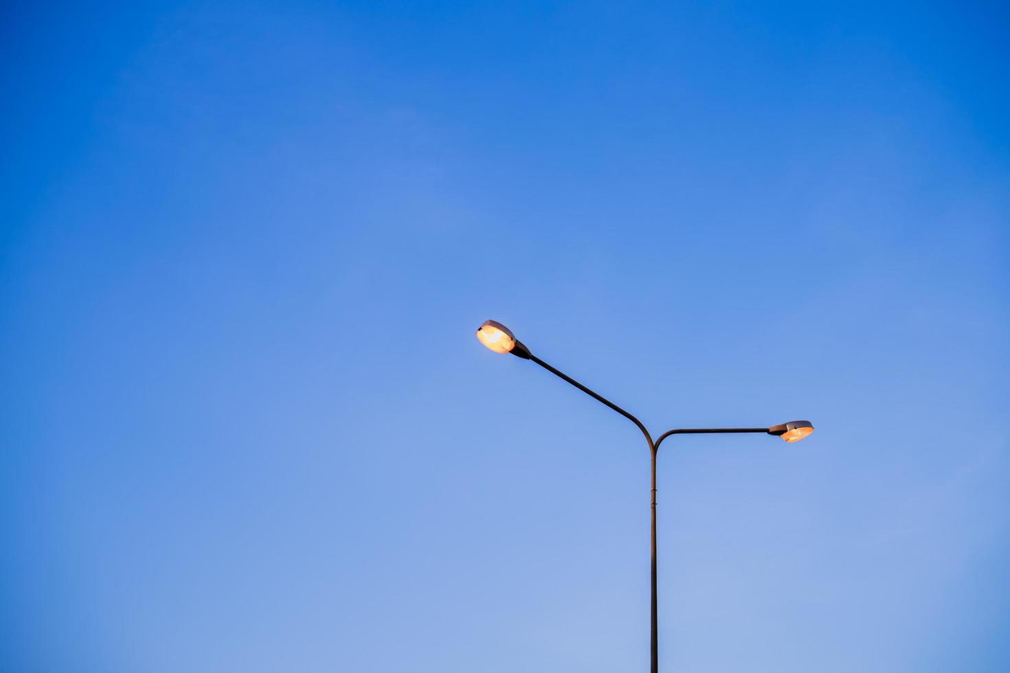 poteau de lampe d'éclairage électrique à côté de la route avec ciel bleu, voyage en soirée avec lumière jaune par lampadaire électrique concept de fond abstrait avec espace de copie photo