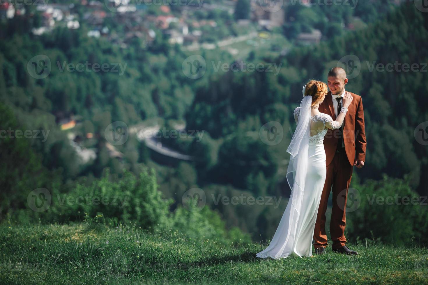 heureux mariés élégants courir et s'amuser dans les montagnes par une journée ensoleillée d'été. magnifique couple de jeunes mariés riant, vrais sentiments. moment romantique émotionnel. photo