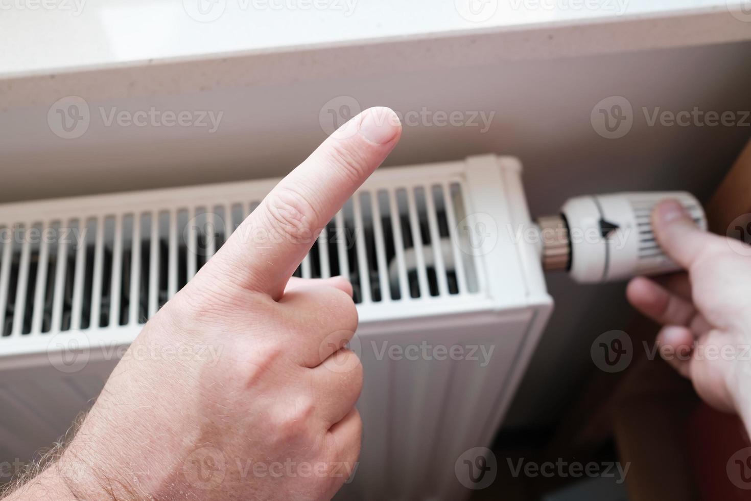 l'index fait un geste de mise en garde et rappelle l'économie, sur fond de radiateur. photo