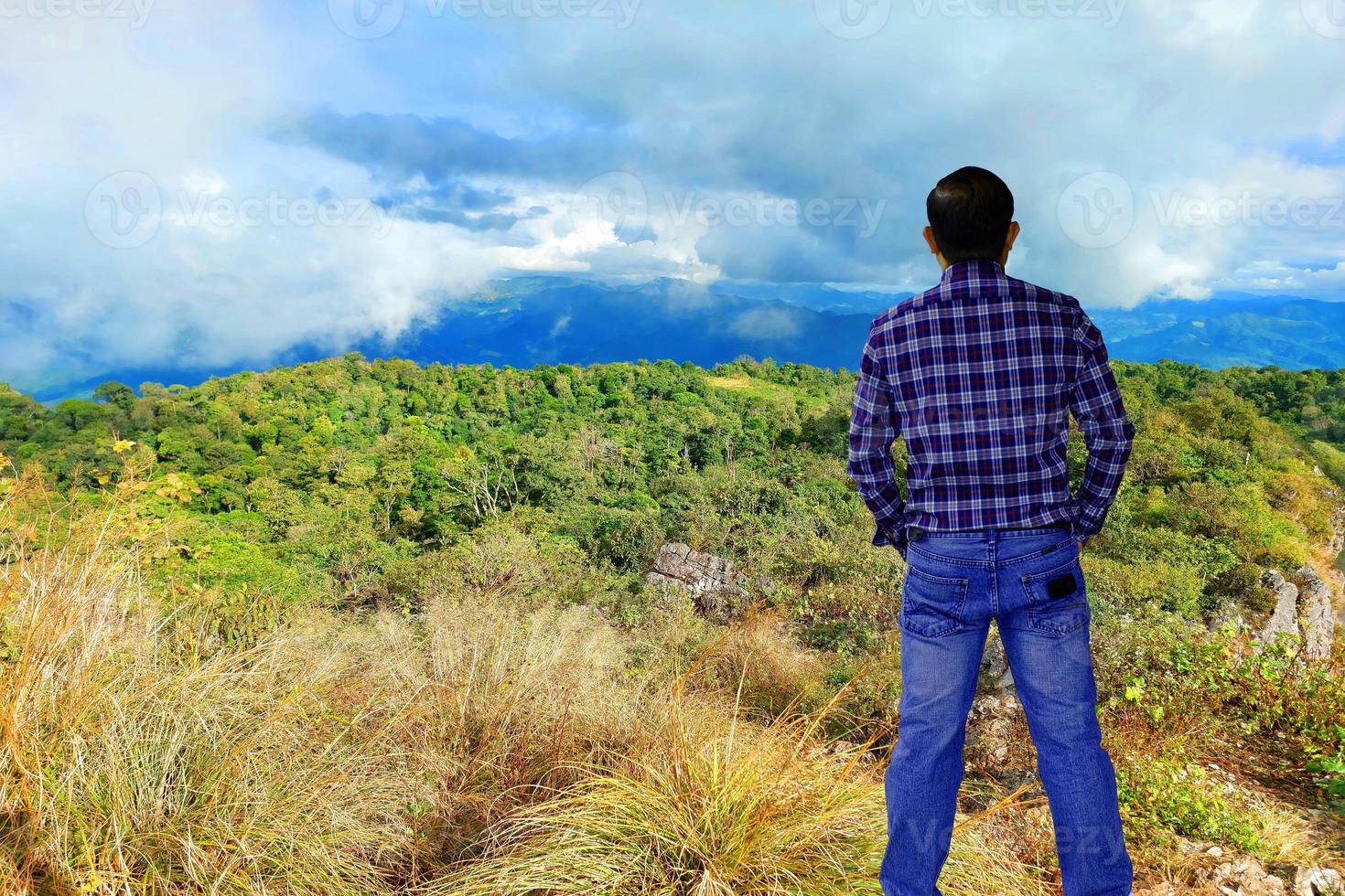 portrait bel homme debout sur la montagne et regardant au loin sur le ciel avec un concept de voyage d'aventure du matin nuages. photo