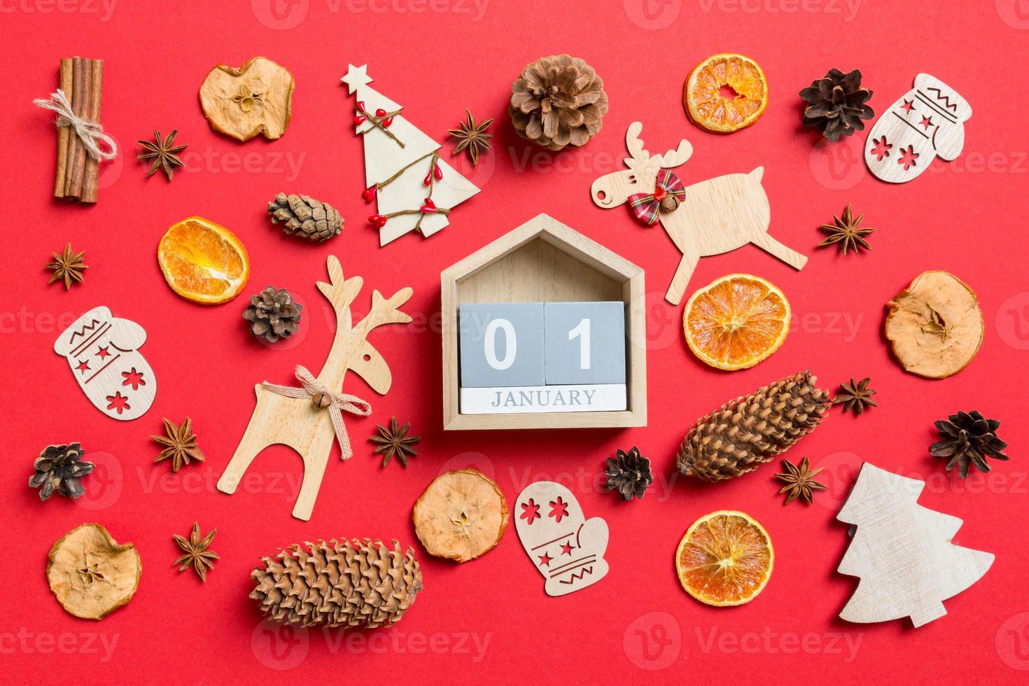 vue de dessus du calendrier, fond rouge décoré de jouets festifs et de symboles de noël rennes et arbres du nouvel an. le premier janvier. notion de vacances photo